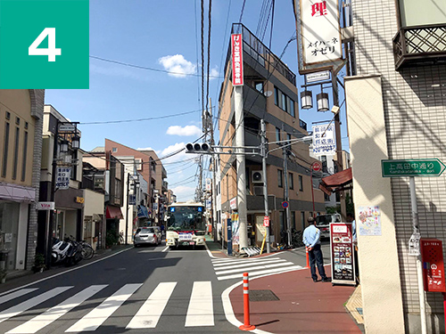 正面にげんき堂鍼灸整骨院の赤い看板がある建物に向かって進みます。